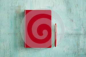 Red book and pen on vintage wooden background