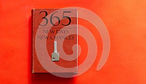 Red book with text 365 New Days New Chances and a key on a red background