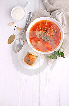 Red borscht soup in white bowl with sour cream