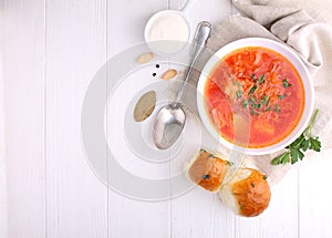 Red borscht soup in white bowl with sour cream