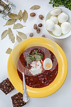 Red borscht soup in yellow plate from top