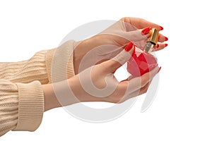 Red bottle of perfume in woman hand with red nails isolated on a white background