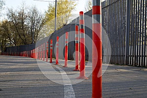 Red bounding posts along the road against a gray trellised fence photo