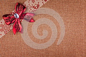 Red bow and diagonal ribbon on brown burlap