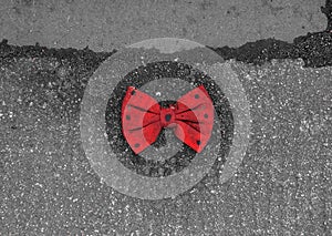 Red bow tie with black dots lying on the pavement