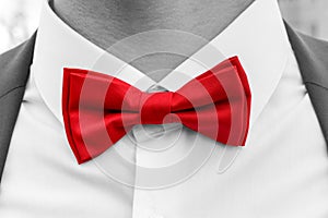 Red bow tie on neck of man, black and white photo with coloured element.