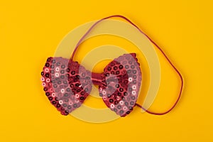 Red bow tie with spangles on light yellow background