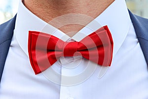 Red bow tie on white shirt.