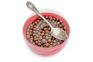 Red bowl with chocolate corn balls and spoon on white