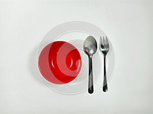 A red bowl and a silver fork are placed on a white background