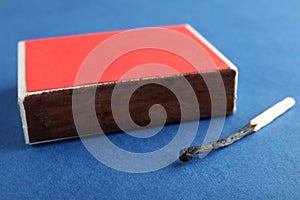 Red box and burnt match on color background