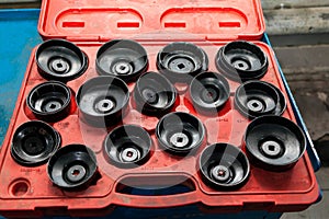 Red Box with a set of removable caps for oil filters of different sizes and diameters for the safe removal of old parts in a