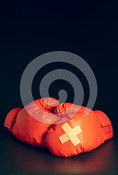 Red boxing gloves in the dark background. Adhesive plaster across each other on boxing gloves.