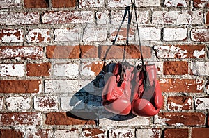 Red boxing gloves on old brick wall