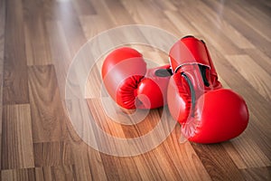 Red boxing gloves on a wood background.