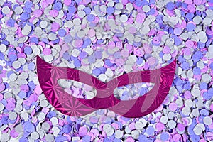 Red brazilian carnival party costume mask on colorful confetti background with space for text photo