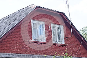 Red brick attic of an old rural house with two white windows
