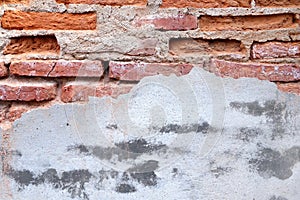 red brick block structure that is plastered with breaking grunge gray concrete wall