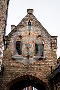 A red brick building with a gable on top an arch in brugge, Belg