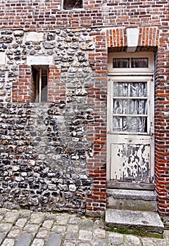 Red brick building with old rustic white wooden doors in Honfleur