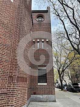 Red brick building with a row of cars parked along the pavement