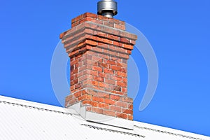 Red brick chimney on white roof
