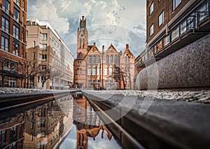 Red brick church building reflected in water.