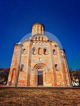 A red brick church with a cylindrical tower, arched doorways, and circular windows under a clear blue sky. Friday Church in
