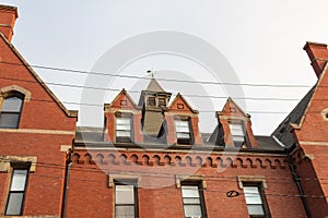 Red brick facade on residential urban apartment building with dormers and cupola