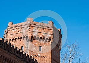 Red brick fortress tower with loopholes and a piece of fence against