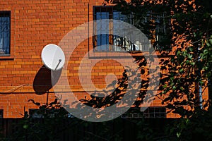 Red brick house with decorative window grates and white satellite dish