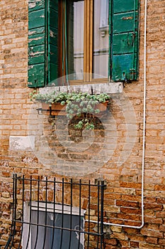 Close-ups of building facades in Venice, Italy. Red brick house wall texture. Wooden window with green shutters and a