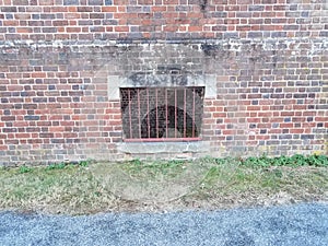 red brick masonry building with window bars and grass