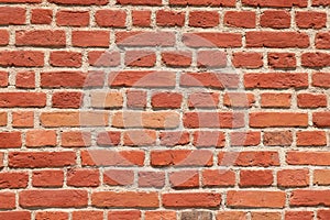 Red brick masonry wall, uneven, broken and black burnt bricks, bright red brick background. Background of red brick wall