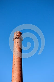 Red brick old chimney of a factory on blue sky background