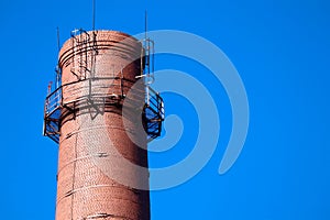 Red brick old chimney of a factory on blue sky background