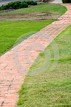 Red brick path crosses grass