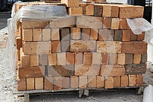 Red brick stowed on a wooden flight at a construction site.