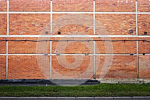 Red brick wall background with green grass