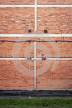 Red brick wall background with green grass