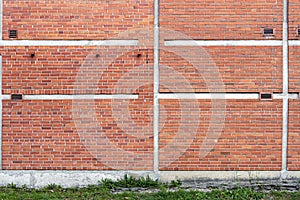 Red brick wall background with green grass