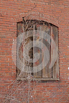 Red brick wall with boarded window