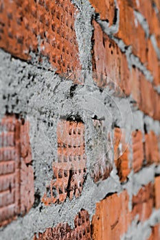 Red brick wall is composed of different bricks in texture