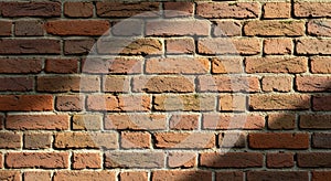 Red brick wall composed of rectangular bricks arranged in a staggered pattern. The