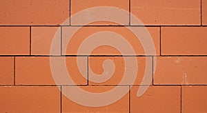 Red brick wall composed of uniformly arranged bricks, each a rectangular shape, in a