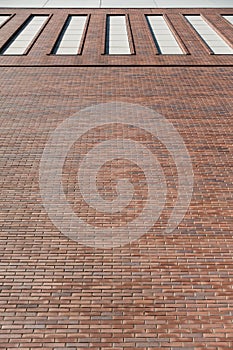 Red brick wall facade background with high windows. Industrial building