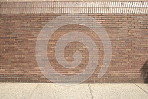 Red brick wall with finishing top bricks and concert sidewalk walkway path