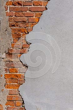 A red brick wall half covered with plaster.