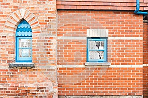 Red brick wall with two blue windows.