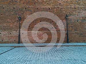 Red brick wall with two high black lamps